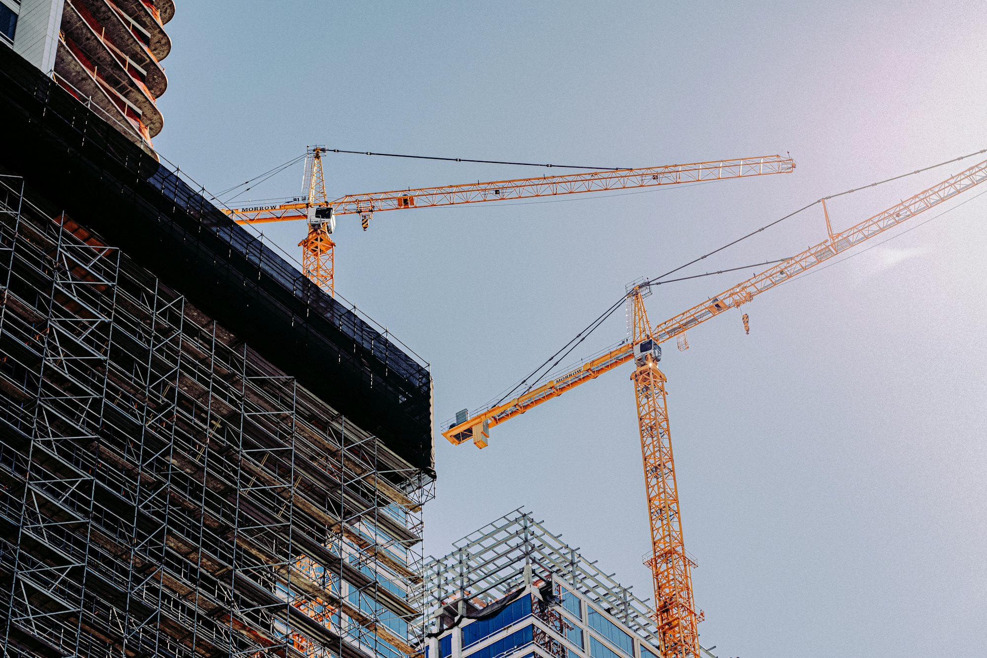 Tower cranes above a high-rise building wrapped in scaffolding
