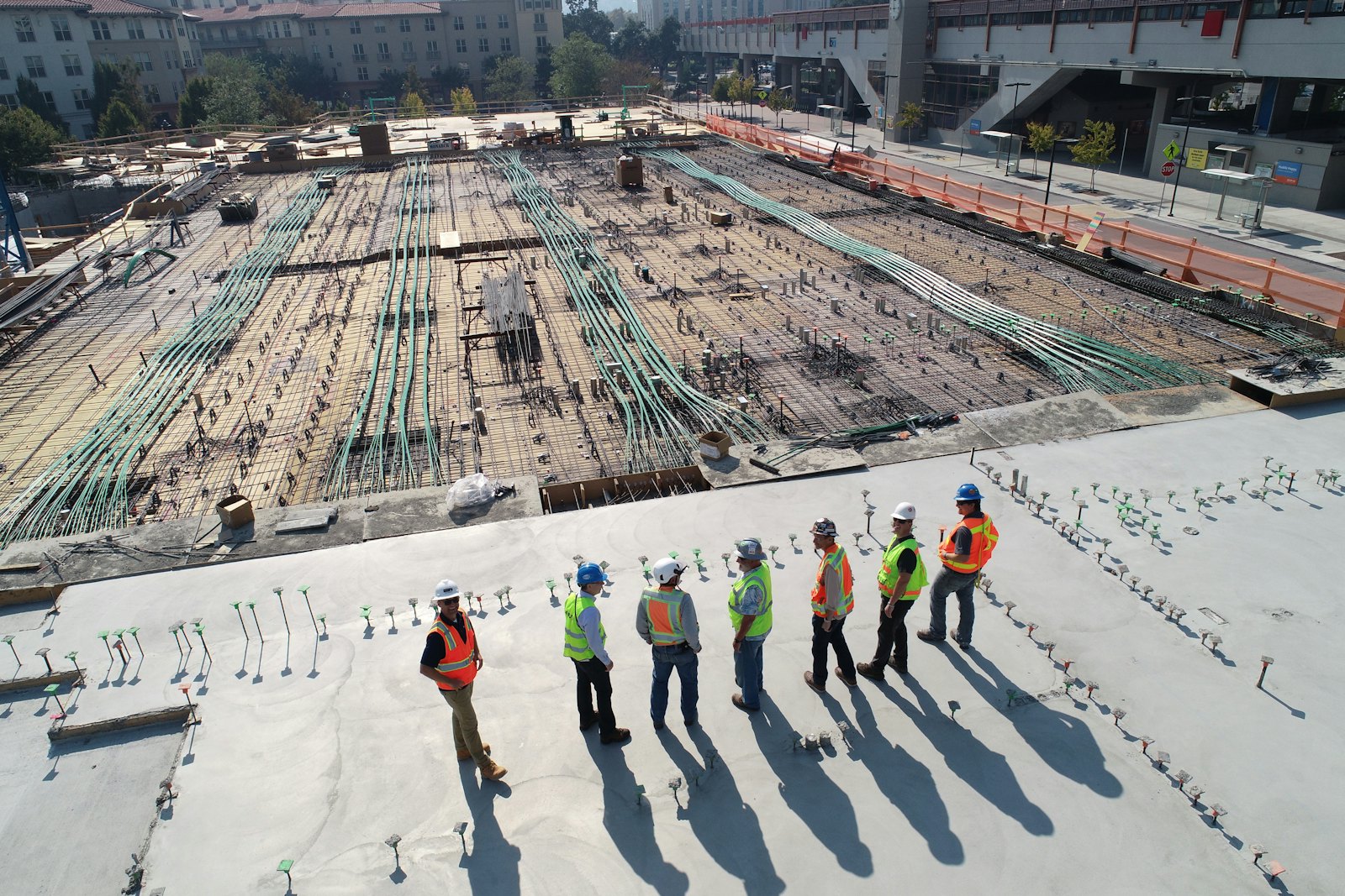 A site team in hard hats and safety vests standing on a concrete deck during a walk-through